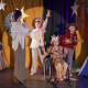4 children on a stage with stars on their heads. One child is a wheelchair user.