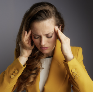 Adult holding their temples and closing their eyes due to overwhelm. 