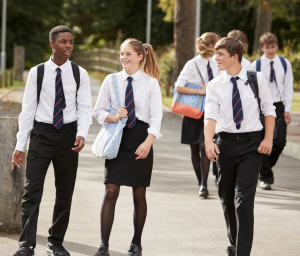 A group of 3 secondary school students walking across a school yard.