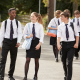 A group of 3 secondary school students walking across a school yard.